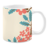 White 11oz ceramic mug featuring a cheerful design with coral pink flowers and teal leaves set against a light cream background. The pattern is framed by a tree branch, creating a playful and vibrant look.