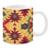 White ceramic 11oz mug featuring a bold geometric design with starburst and diamond motifs in red, green, and burgundy on a warm yellow background.