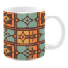 Ceramic mug featuring a tiled geometric pattern in orange, teal, and brown, with diamond and arrowhead shapes arranged in a grid layout.
