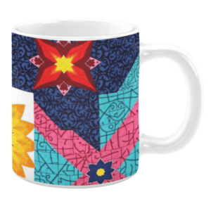 White ceramic mug featuring a bold patchwork design with vibrant floral and geometric patterns in bright shades of red, blue, pink, yellow, and turquoise, creating a dynamic and colorful aesthetic.