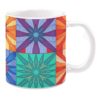 White ceramic mug featuring a colorful patchwork quilt design with bold flower patterns in vibrant shades of orange, purple, blue, and green, creating a lively and dynamic look.