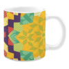 White ceramic mug featuring a vibrant, quilt-like pattern with bold geometric shapes in yellow, green, red, and purple, creating a warm and colorful design inspired by traditional patchwork.