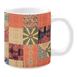 Colorful ceramic mug with patchwork quilt patterns in orange, beige, and dark green tones