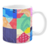 Colorful ceramic mug with geometric patchwork patterns in blue, green, red, and yellow tones