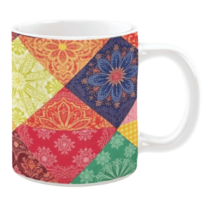 White ceramic mug featuring a vibrant patchwork quilt design with floral and geometric patterns in rich colors such as red, yellow, green, and blue, creating a bold and energetic aesthetic.